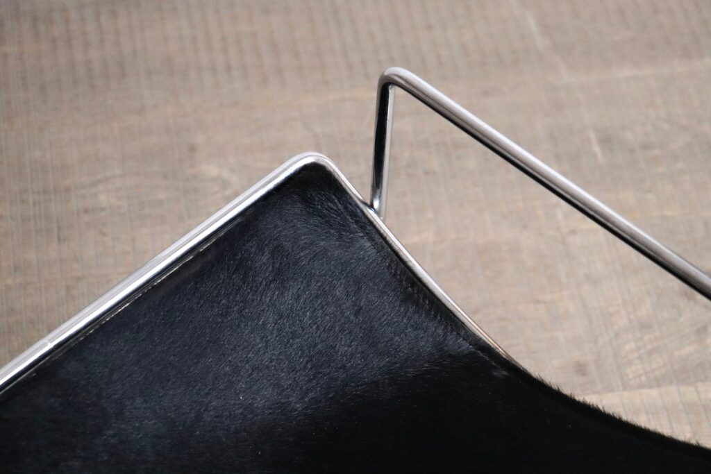 Detail of the black pony upholstery and chrome frame on the Odile Mir Filo chair.