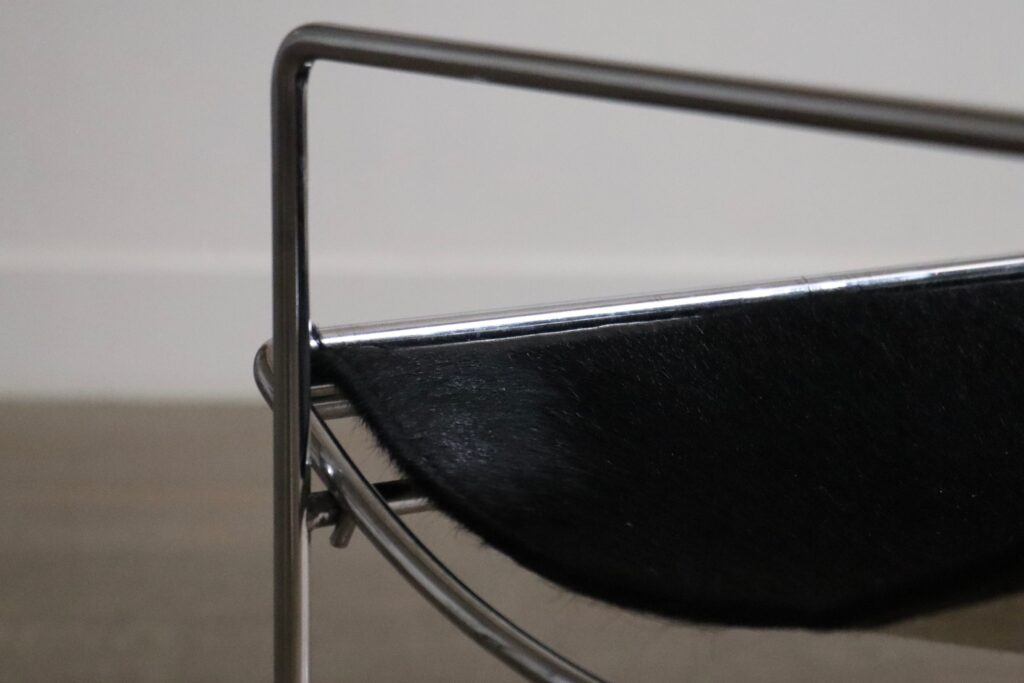 Detail of the black pony upholstery and chrome frame on the Odile Mir Filo chair.