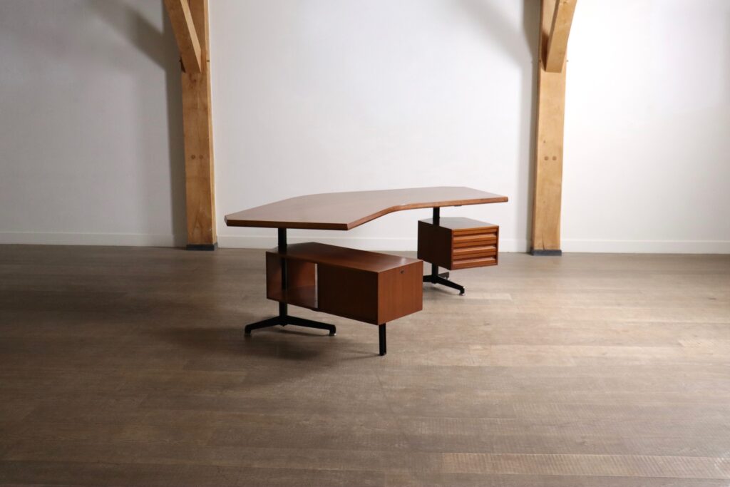 Side view of the Tecno Boomerang desk showing its curved wooden desktop and black metal frame